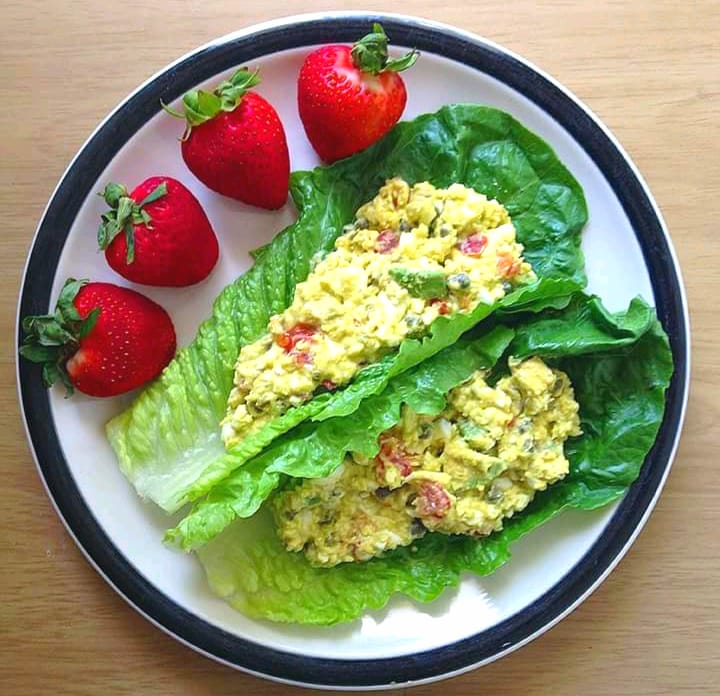 Scrambled eggs with vegetables, salad and strawberries