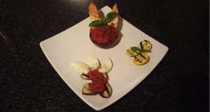 8.	Plate all, and then add the chicken into the hollow aubergine toped with the tomato sauce/Napoletana, garnish with fresh basil and origano.  On this dish, we like to show on the side some of the basic ingredients of the original Parmigiana as a tribute to Italian cuisine of the 16th century.